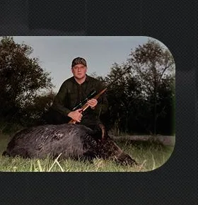 Caçador ao lado de um javali no campo